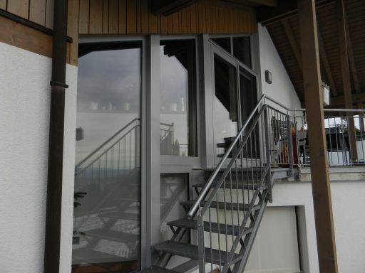 Eingangstreppe zu einem modernen, mehrstöckigen Gebäude mit großen Fenstern.