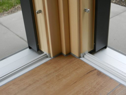 Eckverbindung zwischen Holz- und Aluminiumelementen auf einem Bodenbelag.
