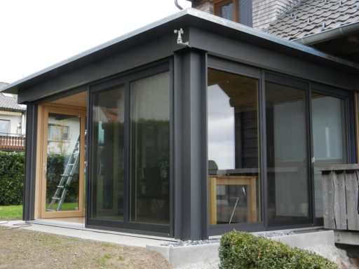 Moderne Glasveranda mit Holzdetails in einem Wohnhaus, umgeben von Garten.