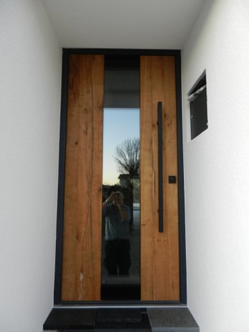 Moderne Holztür mit großem Glasfeld und minimalistischer schwarz-grauer Umrahmung.